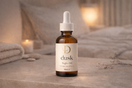 Bottle of Dusk Night Oil on a wooden surface with a soft, warm background